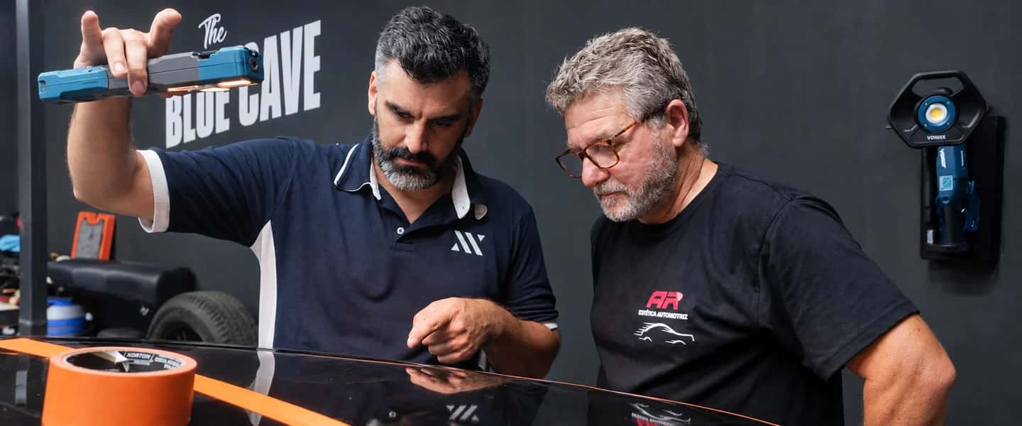 Instructor y alumno inspeccionando pintura con iluminación profesional en The Blue Cave